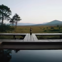 a beer bottle on a picnic table overlooking the water and hills