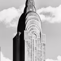 the large building is tall with some clouds in the background