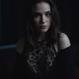 a woman in a dark room with her hands behind her back