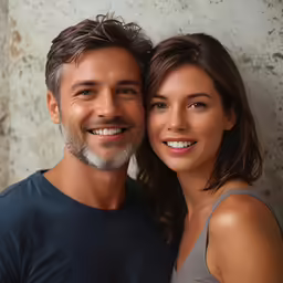 a young man and woman smile as they hold each other