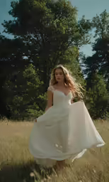 a girl in a long white dress is walking through the grass