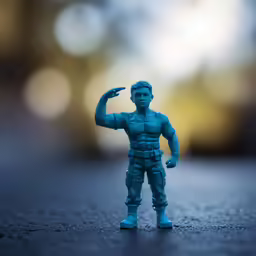 blue figurine posed on dark background in blurry scene