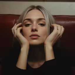 a girl holding her head with one hand as she sits