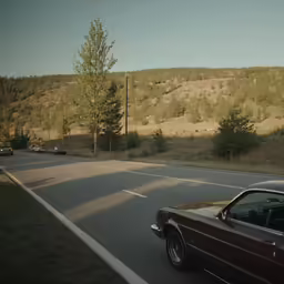 a very nice car on the road near a hill