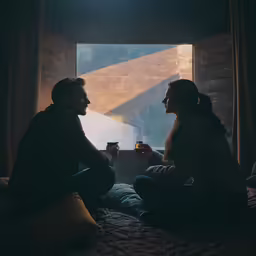 two people are sitting near the window and talking