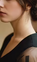 the girl is wearing a black top and has a tattoo on her left arm