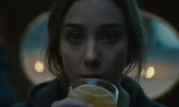a close - up shot of the face of a woman drinking from a wine glass