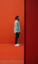 a man standing alone in front of a red wall
