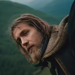 a man wearing a brown and black jacket stares ahead
