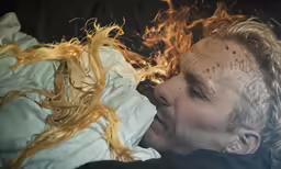 the man is in bed covered by curly hair