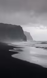 a long dark beach with an ocean view on a gloomy day