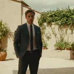 a man in a suit and tie standing by a wall