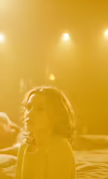 the woman sits on the bed watching the lights shine