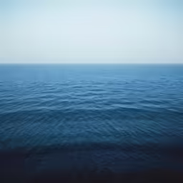 an ocean with a blue hued sky in the background