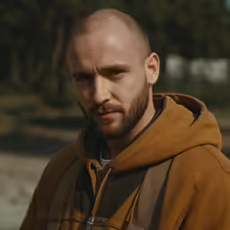 a man looks at the camera with a serious expression