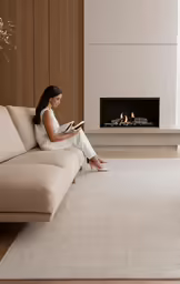 a woman sitting on top of a couch reading a book