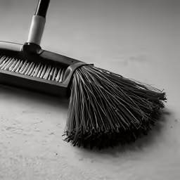 a broom resting on a counter top next to another cleaning brush