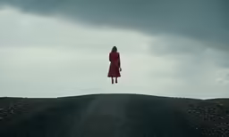 a person wearing a red coat standing on the side of a road