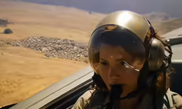a woman wearing glasses sits in the cockpit of a plane