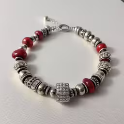 a bracelet with a red bead on the front,a red and silver bracelet with beads