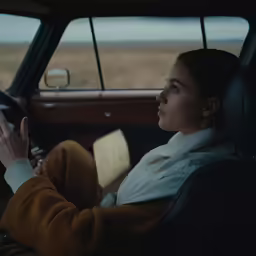 a woman holding onto the steering wheel while riding in a car