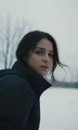 a woman in the snow, gazing back and to the side