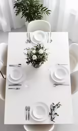 a white table with white chairs and plates
