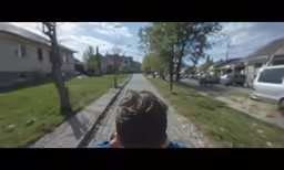 a young boy is riding down the street in front of a house