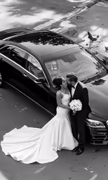 a newly married couple kiss near an array of cars
