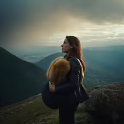 a woman in black jacket carrying a dog up a hill