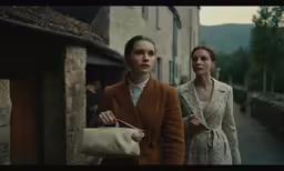 two women walking down the street in a country setting