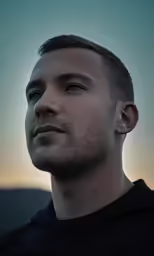 a man with a goatee looks into the distance