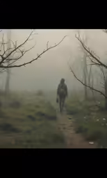 a person walking in a foggy trail on top of a hill