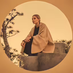 a woman is sitting on the top of a wall looking at her