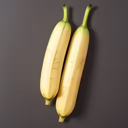 two bananas are hanging upside down on a gray table