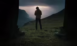 man standing on top of a hill near the mountains
