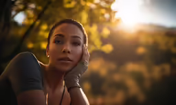 a woman with her hands near her face with the sun behind her