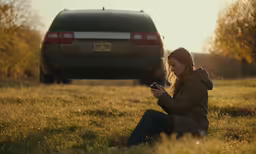 the girl is sitting outside looking at her phone