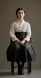 a girl in a black and white dress sitting on a chair