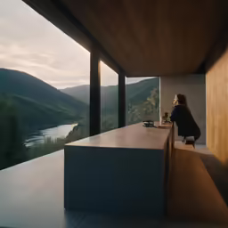 a lady sitting on a chair on the balcony next to the mountain