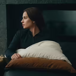 a woman laying on a couch while holding a pillow