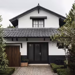 a black and white house with trees and shrubs