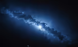 a bird is soaring through the clouds at night