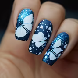 the manicured hand is decorated with blue and white butterfly nail decals