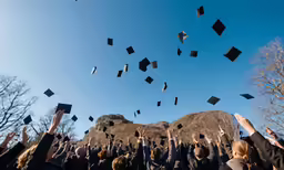 a group of students throwing their graduation caps in the air