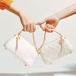 two women holding matching white purses,two people holding handbags each one with a chain around it