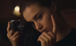 a woman is looking through a camera at something