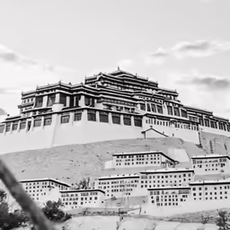 a black and white picture of a building at the top of a hill