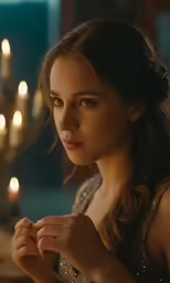 the young woman is holding her hands in a candle lit room