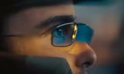 a person wearing glasses looking over their shoulder